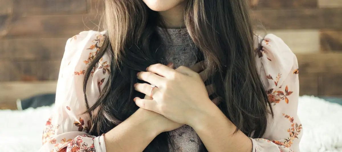 Eine Frau legt ihr Hände über Kreuz auf ihre Brust