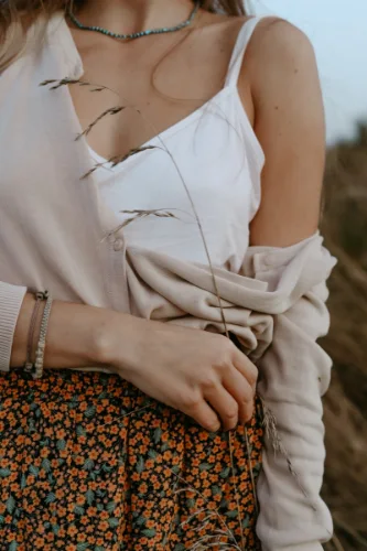 Oberkörper einer Frau mit weisser Bluse, in der rechten Hand hält sie einen Grashalm