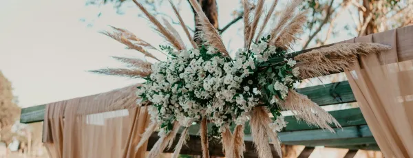 Gesteck mit weissen Blüten an einer Pergola